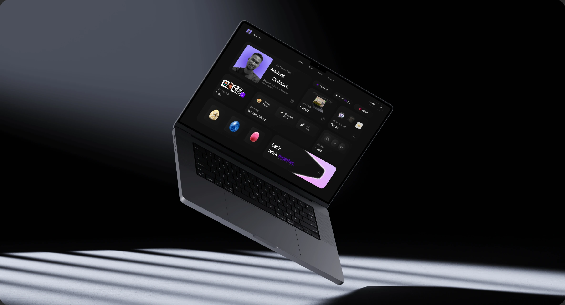 The portfolio home page shown on a MacBook in a dark studio setting